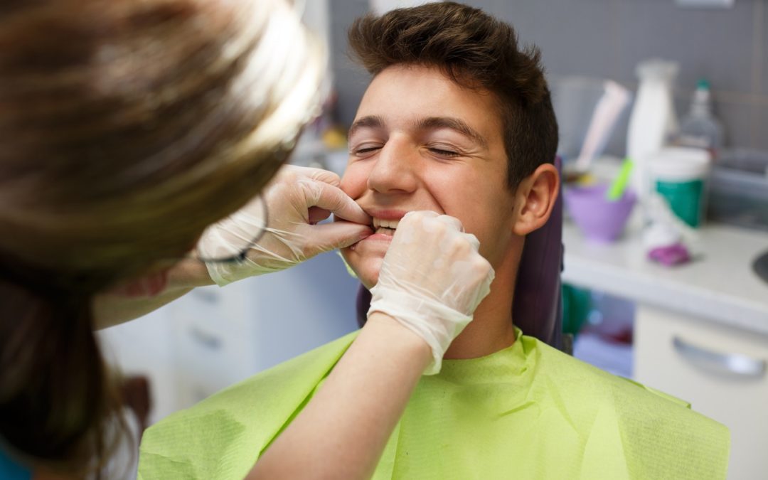 dentystka sprawdza jamę ustną młodego chłopaka